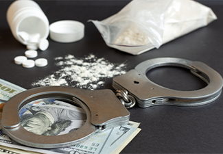 Drugs and handcuffs composition on table
