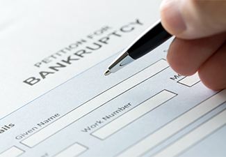 Person filling bankruptcy form with pen