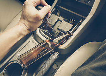 Bottle of Alcohol on side while man drives car