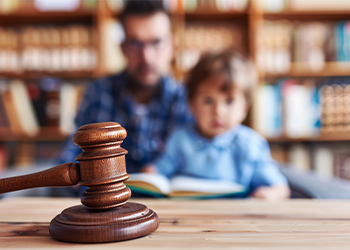 Gavel close up with blurred child and father in background