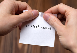 Hands of a man tearing a piece of paper with inscription criminal record