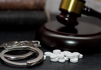 Judge's gavel with handcuffs, drugs on wooden table