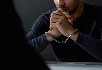 Criminal man with handcuffs in interrogation room