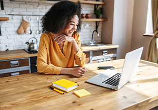 A cheerful mixed-race girl uses laptop for remote work