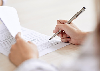 Person reading and signing contract document