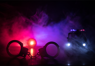Closed handcuffs on the street pavement at night with police car