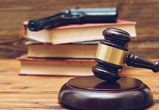Judge gavel, law books and gun on a wooden background