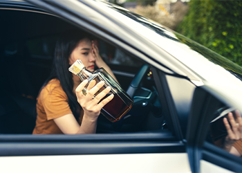 Drunk teenage girl with alcohol bottle on hand