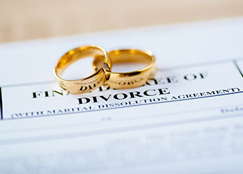 Two broken golden wedding rings and divorce decree document