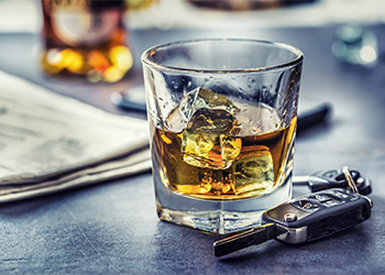 Car keys and glass of alcohol on table