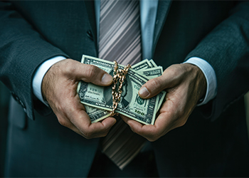 Man in suit holding dollar bundle in hand