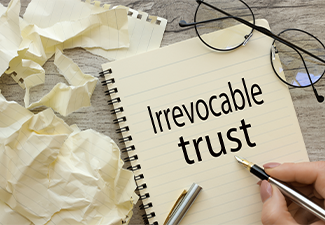 Top view of a page with text. woman writes words Irrevocable trust