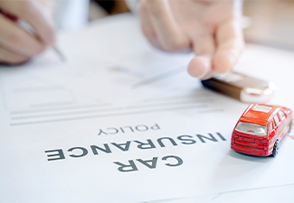 Car insurance policy with red car toy and blur image of man hand