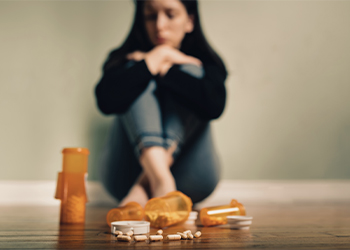 Prescription pills and sad women in background