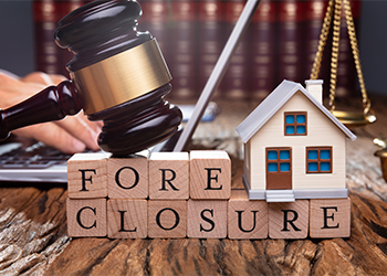 Foreclosure word formed by wooden blocks, model house and gavel