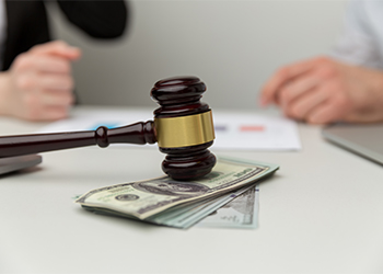 Wooden gavel and money with divorced couple in background
