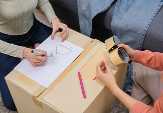 Group of friend sorting and packing clothes into a donation box