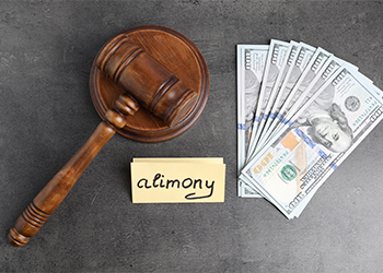 Card with word Alimony, dollar banknotes and wooden gavel