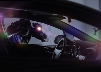 Thief with flashlight looking inside car