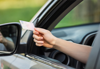 Person hand out of the car window holding the driver license