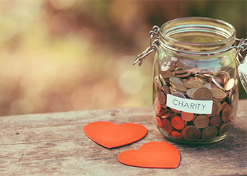 Jar with coins and term charity with heart shape on desk