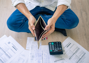 Businessman sitting on floor with empty wallet and financial documents