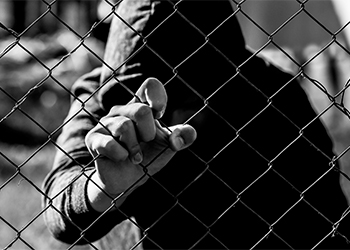 Teenage boy behind metal wires in detention center