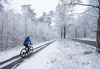 Man on mountain bike follows trail in snow during winter