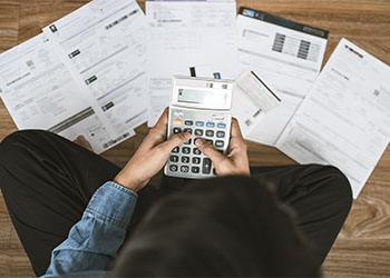 Man with calculator and unpaid bills in home