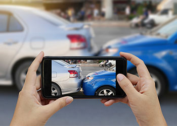 Hands using smartphone to take photo of car accident site