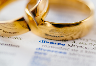 Two broken wedding rings on divorce word in dictionary