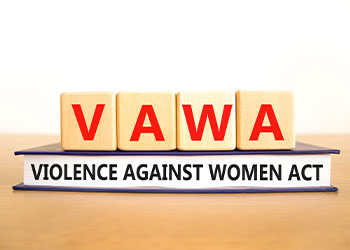 Wooden blocks spell 'VAWA' atop book labeled Violence Against Women Act