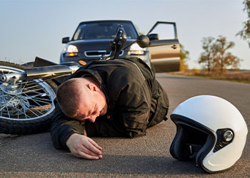 Motorcyclist lying on road after accident with car