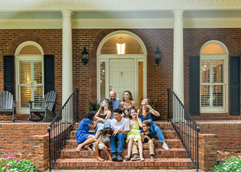 Large, blended family sitting in front steps of house