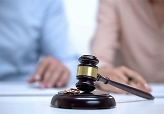 Marriage rings and gavel closeup, spouses signing divorce document