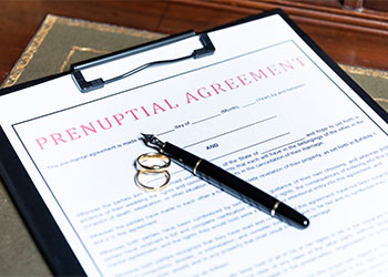 Prenuptial agreement form with wedding rings and pen