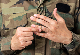 Hands of soldier male who is about to taking off his wedding ring