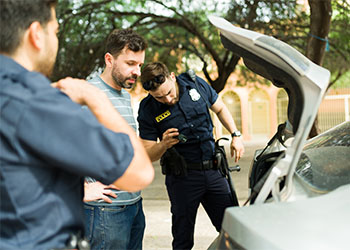 Police searching inside car trunk of a man