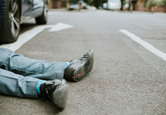 Person lying on the ground after a car accident