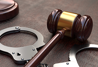 Gavel and handcuffs on wooden table background