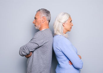 Old couples sitting back-to-back after argument