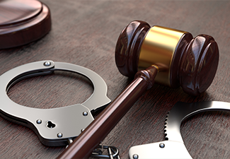 Gavel and handcuffs on wooden table background