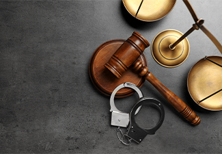 Judge's gavel, handcuffs and scales on grey background