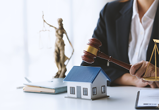 Lawyer holding gavel near model house and justice scale