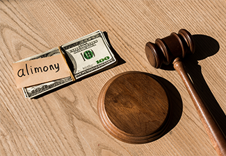 Gavel near dollar banknotes and paper with alimony lettering