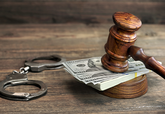 Dollar banknotes, handcuffs and judge gavel on wood table