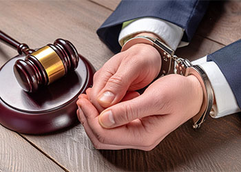 Handcuffed man with gavel on table
