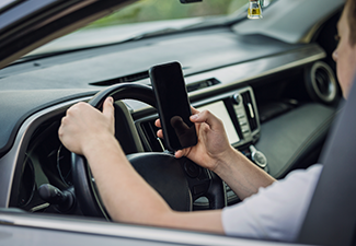 Driver guy distracted by his phone while in front of the steering wheel
