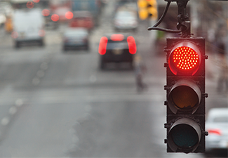 Traffic light in the city with red signal on the background of the road