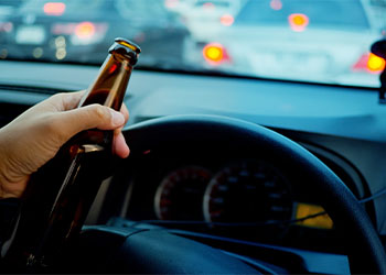 Man with beer bottle in hand driving in highway